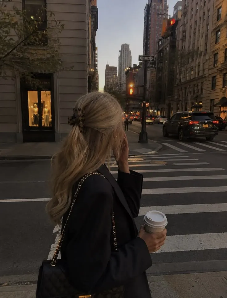 Woman walking a New York street at golden hour with a coffee